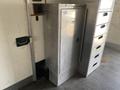 A metallic equipment cabinet with a sleek design featuring a single front door and ventilation slots, likely used for storage or utilities in a commercial or industrial setting