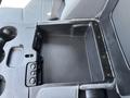 A close-up view of the center console storage compartment in a 2013 RAM 2500 featuring a textured bottom and buttons for various functions