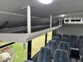 Interior view of a 2020 Chevrolet Express showing overhead storage rack and a row of fabric-covered seats with a blue and green wave pattern