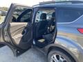 A gray 2016 Ford Escape with the driver's side door open revealing the interior seating area and back seat