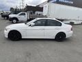 A white 2011 BMW 3-Series parked with tinted windows and black alloy wheels