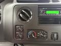 Dashboard controls of a 2015 Ford Econoline featuring air conditioning knobs and a radio display