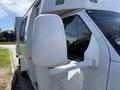 A white 2013 Ford Econoline van with a side mirror extending from the driver's side