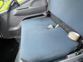 A blue cloth seat in a 2012 Mitsubishi Fuso FE truck with a visible seatbelt and a roll of tape nearby
