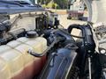 Close-up of the engine components of a 2017 Ford F-650 Super Duty showing coolant reservoir hoses and air intake elements