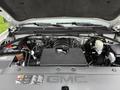 The image shows the engine compartment of a 2015 GMC Sierra 1500 with a black engine cover and various components such as wires tubes and fluid reservoirs visible