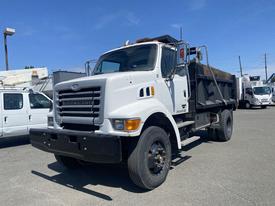 A 2006 Sterling L7500 dump truck with a white cab and black dump bed positioned in a parking lot