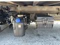 A 2022 Isuzu NQR showing a fuel tank with a blue cap on the left and a tool box on the right mounted under the truck bed