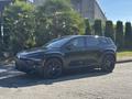 A 2023 Fisker Ocean electric SUV in black is parked, featuring sleek lines and a modern design with distinctive wheels and grille