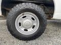 A close-up view of a silver wheel and rugged tire of a 2015 Ford F-250 SD showcasing its tread pattern and rim design