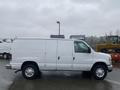 A white 2011 Ford Econoline van with sliding side doors and chrome wheels parked on a wet surface
