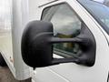 A close-up of the side mirror of a 2022 Ford E-450 with a sleek black design displaying water droplets on the surface