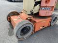 A 2009 JLG E300AJP aerial work platform with orange and beige colors featuring large rubber tires and directional arrows on the base