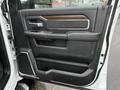 A black interior door panel of a 2024 RAM 5500 featuring wood and metal accents with controls for window and door locks