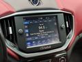Close-up of the infotainment system in a 2016 Maserati Ghibli displaying radio information and controls