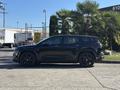 A black 2023 Fisker Ocean SUV is parked, showcasing its sleek design and sporty features with distinct wheels and a modern silhouette