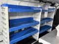 A 2019 Ford Transit interior with blue shelving units mounted on the walls for storage