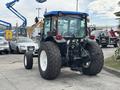 A 2009 New Holland T4020 tractor with large rear wheels and a blue roof is positioned in the foreground showcasing its rear view and hydraulic components