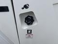 A fuel cap labeled "DIESEL FUEL" secured with a black knob on a white machine with a warning label beneath it