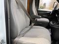 Two front seats of a 2015 GMC Savana with seat belts fastened visible from the driver's side
