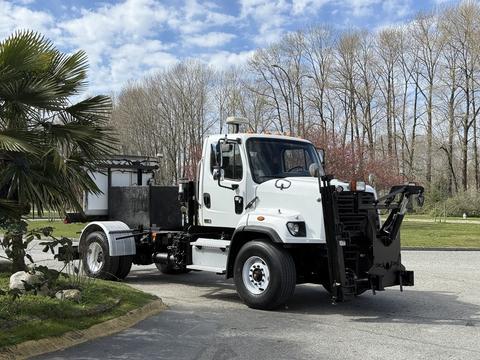 A white 2016 Freightliner 108SD truck with a snow plow attachment and a flatbed in the rear, featuring large wheels and a robust front grille