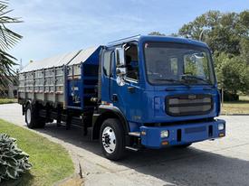 A blue 2017 Autocar Xpert truck with a flatbed and metal sides is positioned at an angle showcasing its front and passenger side