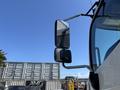 A 2020 Hino 338 truck with large side mirrors reflecting light
