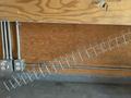 A metal rack with a diagonal arrangement of wire shelves is attached to a wall with electrical outlets and conduits visible nearby