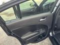 A 2015 Dodge Charger with an open driver's side door showcasing the interior door panel and window controls