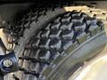 Close-up of a rugged tire on a 2015 Hino 358 featuring deep treads designed for off-road or heavy-duty use