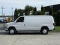 A white 2013 Ford Econoline van parked on a concrete surface with a sleek design and visible sliding door