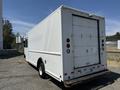 A 2012 Ford Econoline delivery truck with a white exterior and a rear entrance door parked on a gravel surface