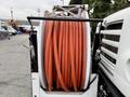 A large reel with orange hoses coiled neatly, mounted on the rear of a 2006 Sterling L7500 truck