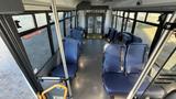 Interior view of a 2021 Ford Transit bus featuring blue seats and a wheelchair lift at the rear