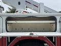A 2012 International 7300 Workstar truck with an open utility bed revealing storage compartments and equipment mounting points