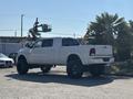 A white 2018 RAM 3500 pickup truck with large black wheels parked at an angle displaying its side and rear view