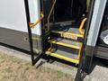 2020 Chevrolet Express bus with open doors revealing step entrance and yellow handrails