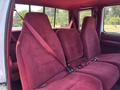 Red upholstered interior of a 1995 Ford F-250 with two rows of bucket seats and seat belts visible in the foreground
