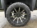Close-up of a black rim and tire from a 2022 GMC Sierra 3500HD featuring multi-spoke design and aggressive tread pattern