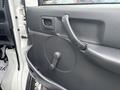The interior door panel of a 2010 Suzuki Carry featuring a door handle a crank window mechanism and storage pocket
