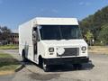 A white 2012 Ford E-450 delivery truck with a boxy design and large windshield parked on a road