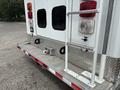 The rear of a 1994 GMC Vandura 3500 featuring a metallic step bumper with a diamond plate design two rear lights and a tow hitch setup