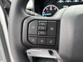 Close-up of the steering wheel controls in a 2023 Ford F-450 Super Duty featuring buttons for cruise control audio settings and other functionalities