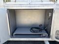 An open compartment of a 2008 Workhorse W62 with a sliding tray and a coiled cable inside