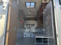 Interior view of a 2008 International 4400 with metal shelves cabinetry and a flat storage area along the floor