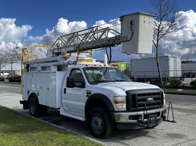 A white 2008 Ford F-550 bucket truck equipped with a large extendable boom and an enclosed storage area on the back