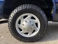 Close-up of a silver alloy wheel with a rugged tire showcasing deep treads mounted on a 2013 Ford E-350 Super Duty