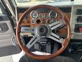 A wooden steering wheel with a silver center and multiple gauges on the dashboard of a 2008 Peterbilt 340 truck