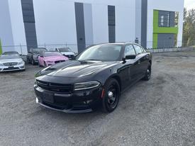 A black 2015 Dodge Charger is parked with its front angled toward the viewer showcasing its sleek design and sporty grille