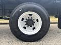 A close-up of a large black tire with a white rim mounted on a 2018 Ford F-750 showcasing the tread and bolt pattern